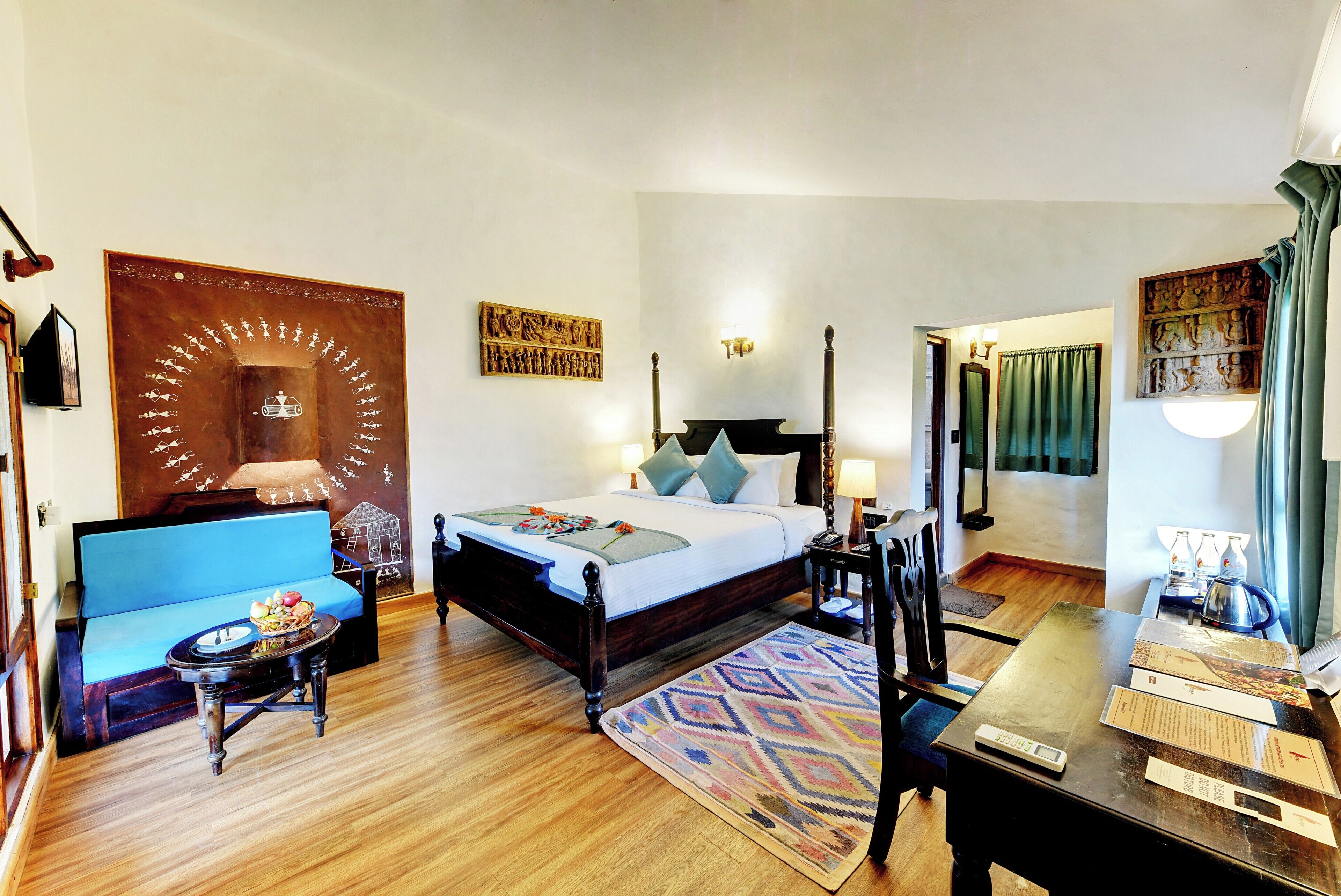 A hotel room with a bed, a sofa, a desk with a kettle, and a table with a scale.