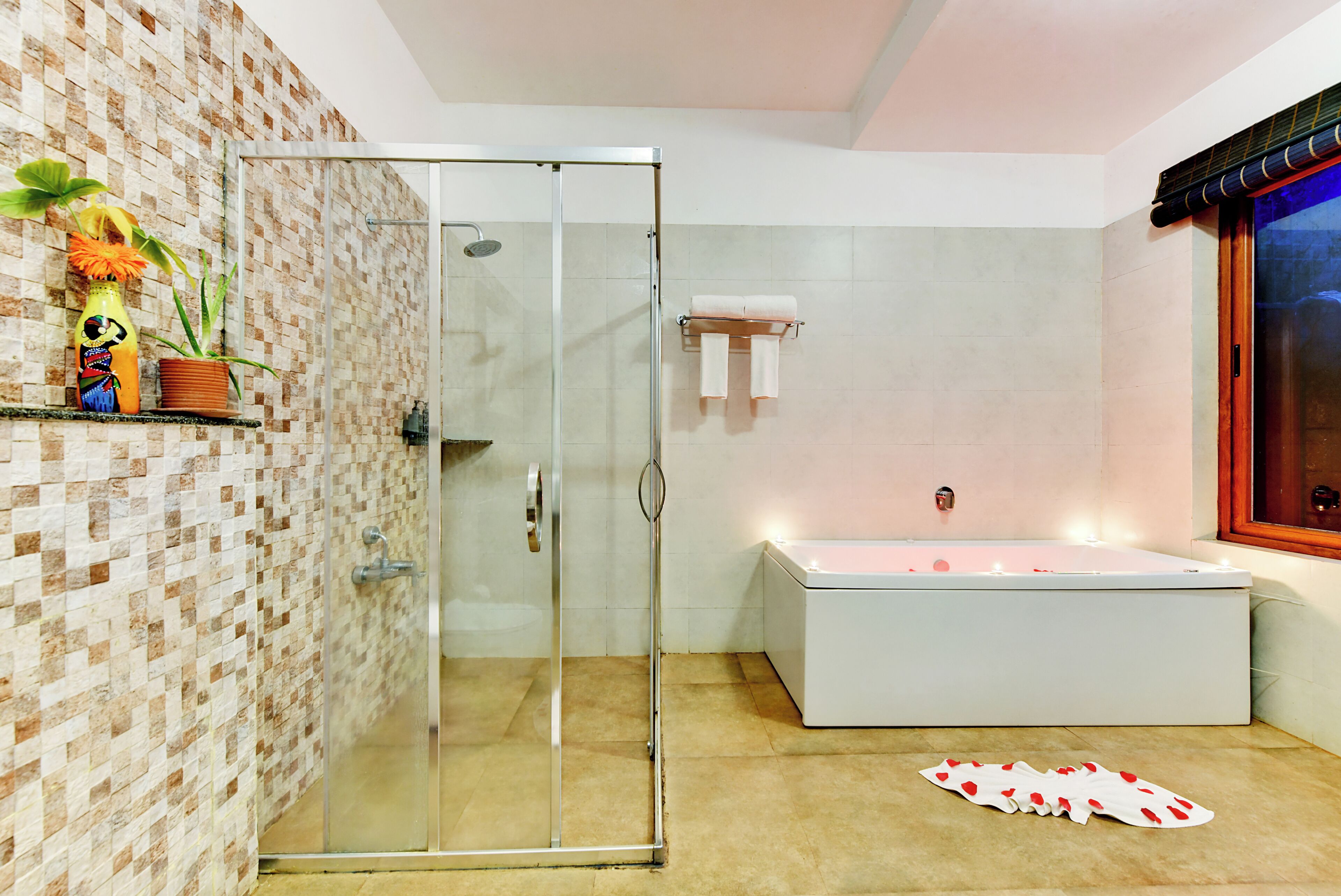 A modern bathroom with a glass shower enclosure, a white bathtub, and a tiled wall.