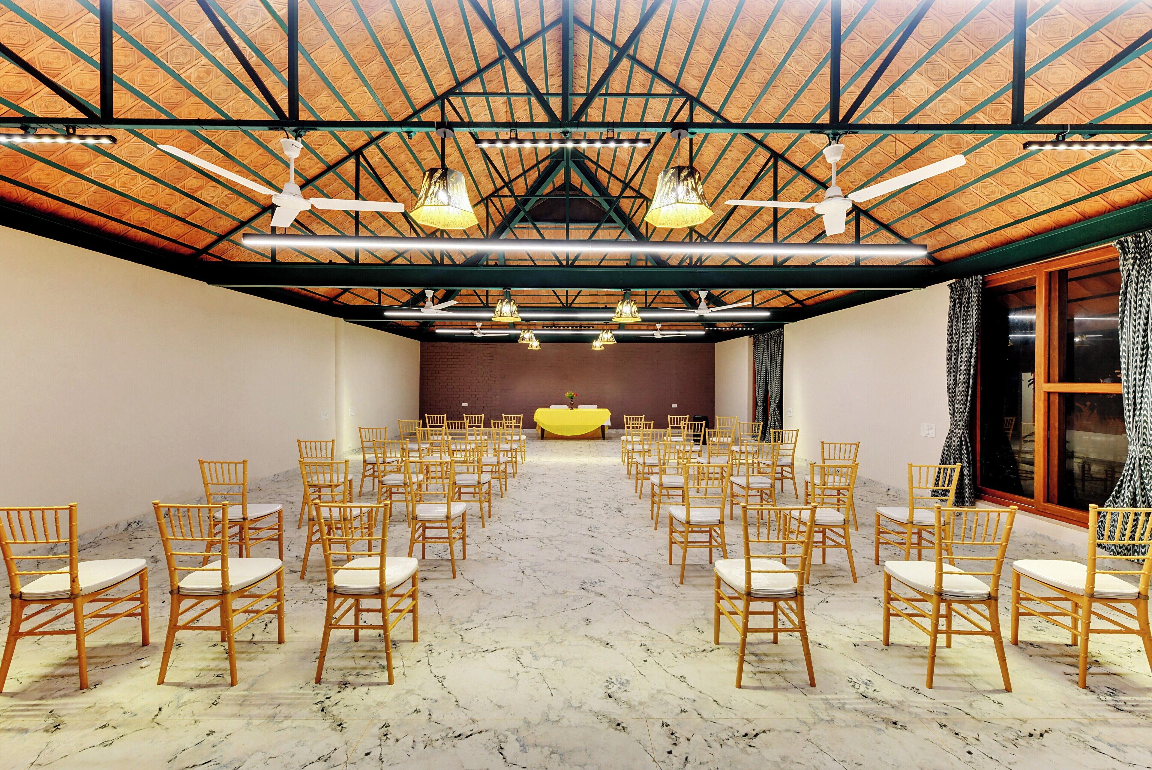 Un salón de conferencias con techo alto, disposición de asientos y un escenario.