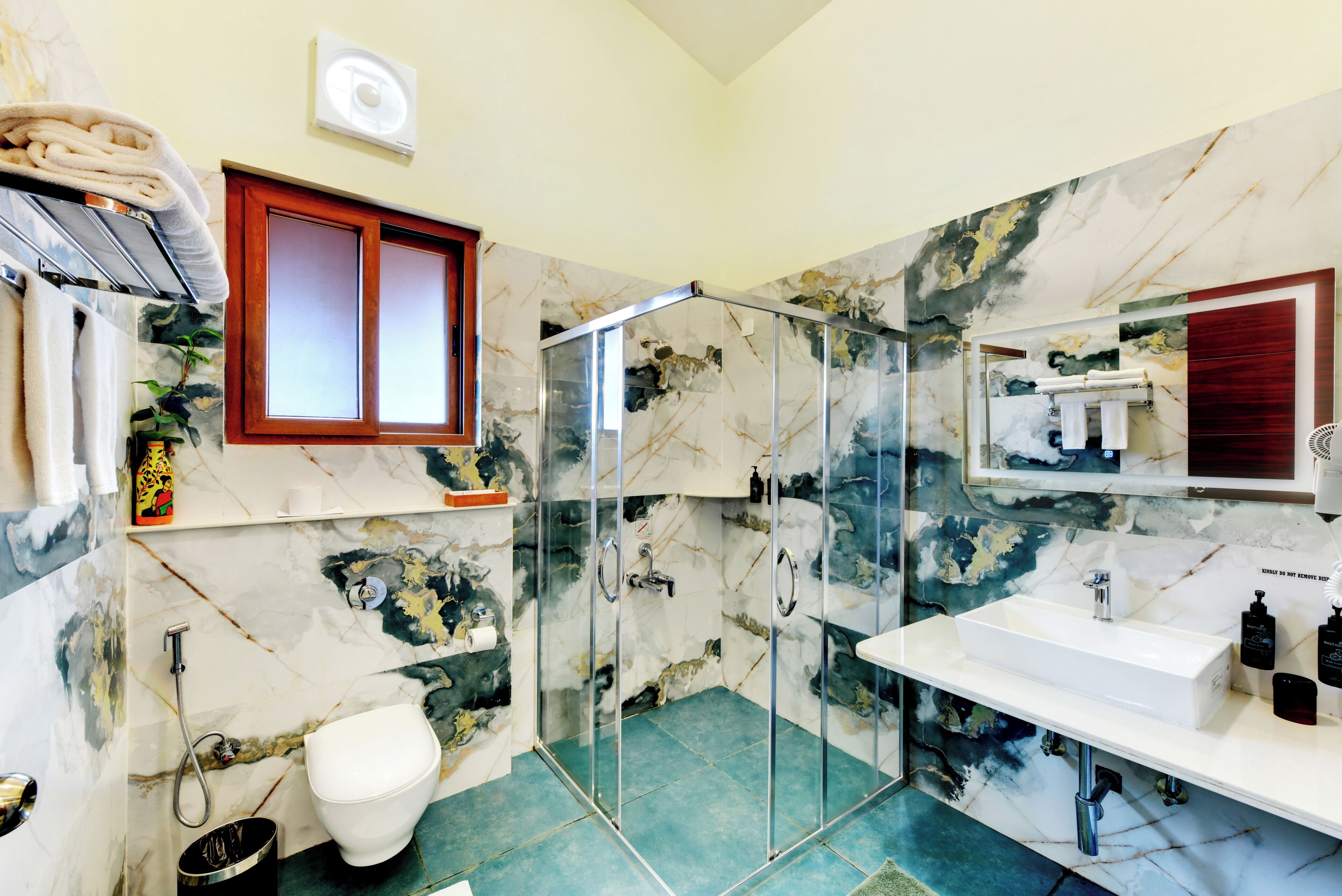 Une salle de bain avec une douche à parois de verre, des toilettes, un lavabo et un miroir.