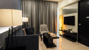 A modern living room with a sofa, armchair, coffee table, and a TV mounted on the wall. - AR Suites Fontana Bay (Pune)