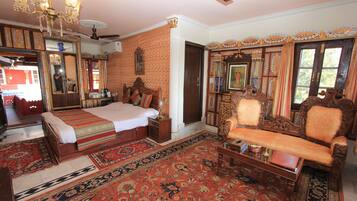 A traditional room with a bed, a sofa, a chandelier, and a large mirror.