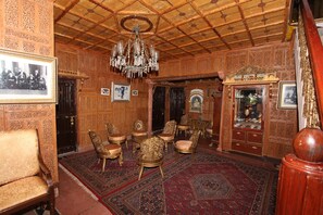 A room with ornate wooden paneling, a chandelier, and several antique chairs. - WelcomHeritage Grace Hotel (Dharamshala)