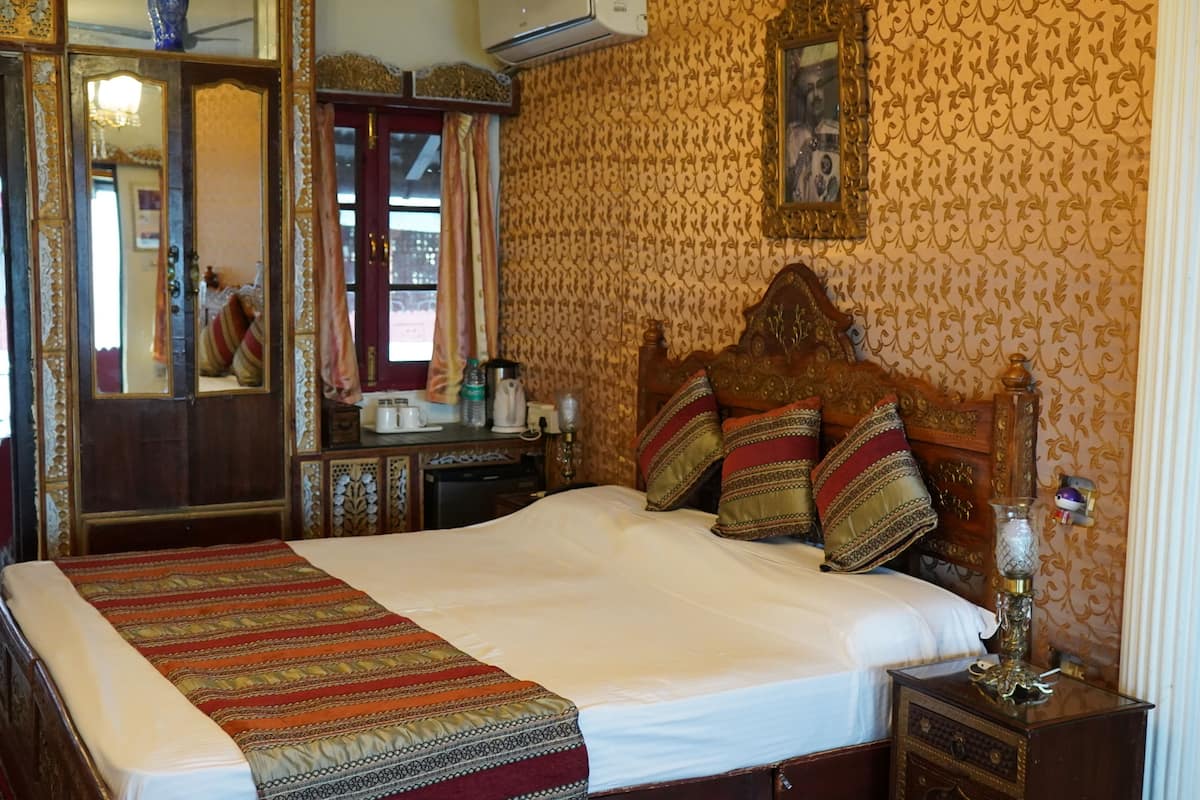 A traditional room with a large bed, ornate wooden headboard, and a mirror.