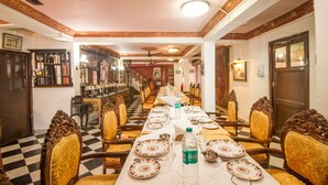 A long dining table with chairs, set for a meal. - WelcomHeritage Grace Hotel (Dharamshala)