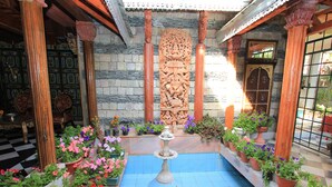 A courtyard with a fountain, potted plants, and a stone wall with carvings. - WelcomHeritage Grace Hotel (Dharamshala)