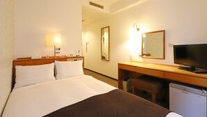 A hotel room with a bed, a desk with a television, a mirror, and a small refrigerator. - Smile Hotel Tokyo Ayase Ekimae (Tokyo)