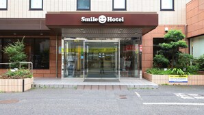 The exterior of Smile Hotel with a glass entrance, a brown awning, and a signboard. - Smile Hotel Tokyo Ayase Ekimae (Tokyo)