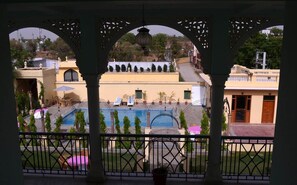 A view of a pool area with a pergola structure, a swimming pool, and surrounding buildings.