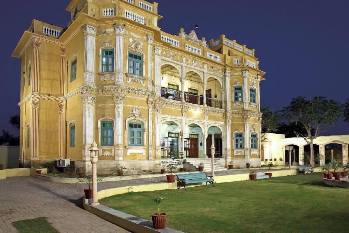 A large, ornate building with multiple balconies and a well-maintained lawn.