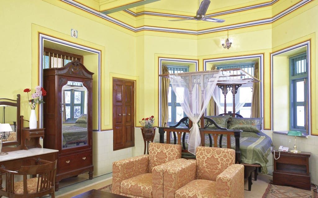 Une pièce comprenant un lit, une chaise, un bureau et un miroir.