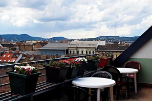 A rooftop terrace with a view of a cityscape, featuring a table and chairs, and potted plants. - Silver Hotel Budapest City Center (Budapest)