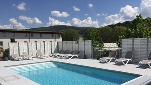 A rectangular swimming pool with clear blue water, surrounded by white lounge chairs. - Brit Hotel Confort Marvejols (Marvejols)