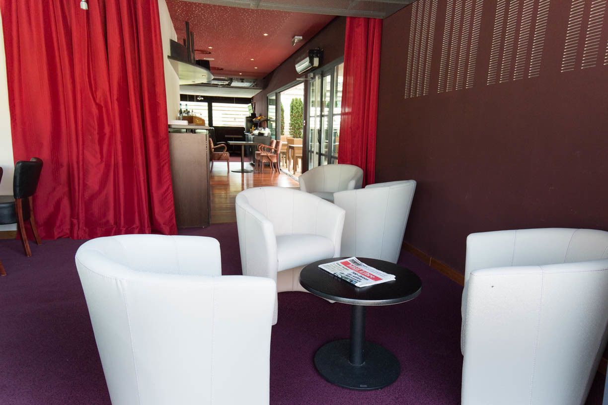 Un interior moderno con sillas de cuero blancas y una mesa redonda, cortinas rojas y vistas al área de comedor.