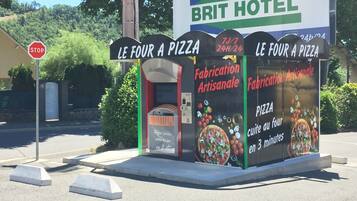 A roadside sign for a pizza restaurant with a stop sign nearby.
