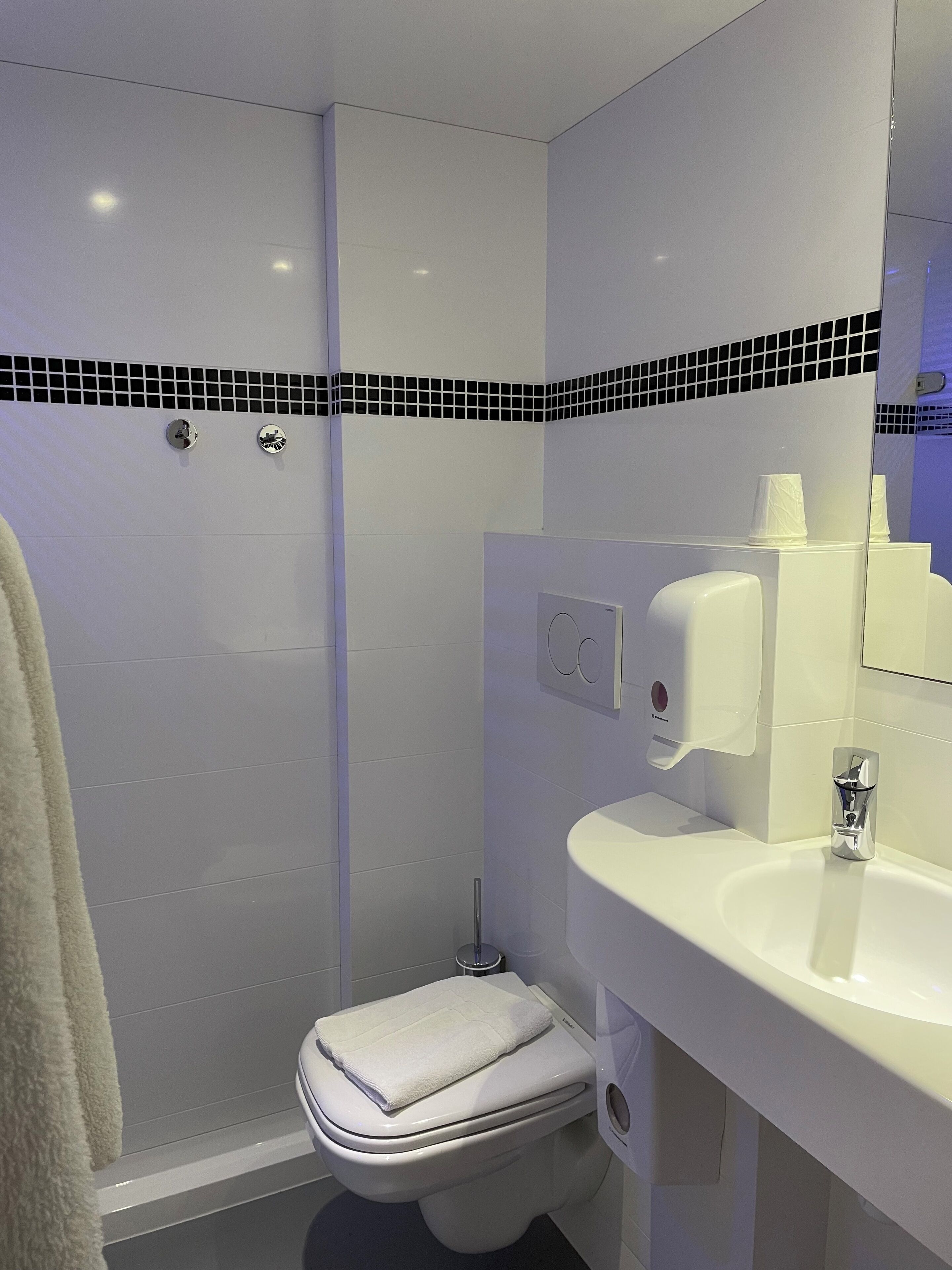 A modern bathroom with a toilet, sink, and hand dryer.