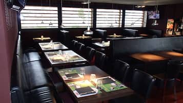 Interior de restaurante con cabinas y mesas, algunas con menús y vasos.