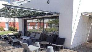 An outdoor seating area with modern furniture, a pergola, and a view of the surrounding landscape. - Brit Hotel Confort Marvejols (Marvejols)