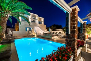 Een buitenzwembad, parasols bij het zwembad en ligstoelen