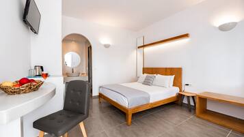 Una habitación de hotel moderna con cama, un escritorio con una cesta de fruta, una silla y un banco de madera.