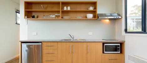 A modern kitchen with wooden cabinets, a stainless steel refrigerator, a microwave, and a built-in oven.