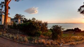 A coastal road with a house and RVs parked nearby.