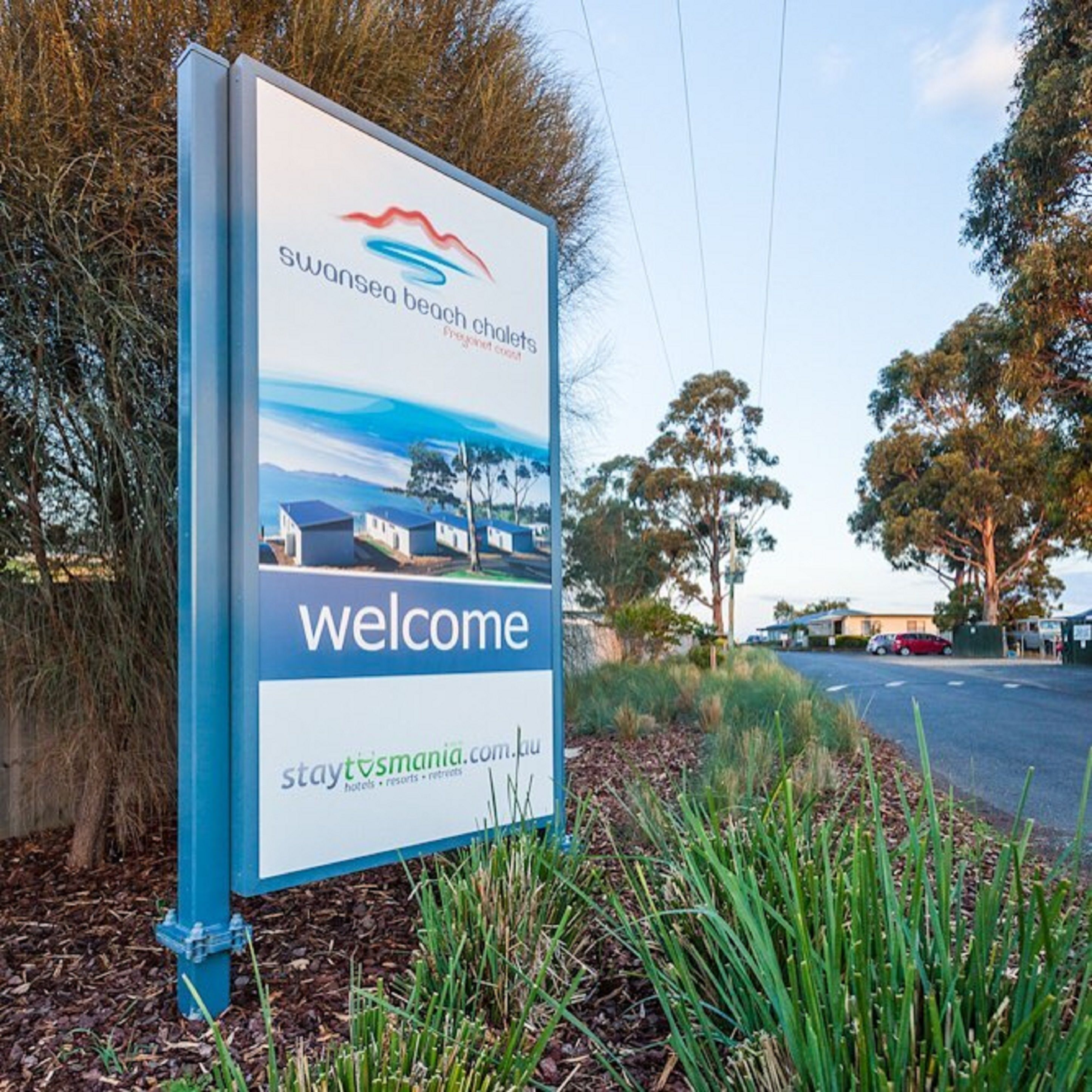 A welcome sign for Swansea Beach Chalets with a website address.