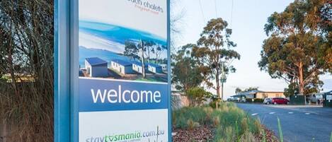 A welcome sign for Swansea Beach Chalets with a website address.