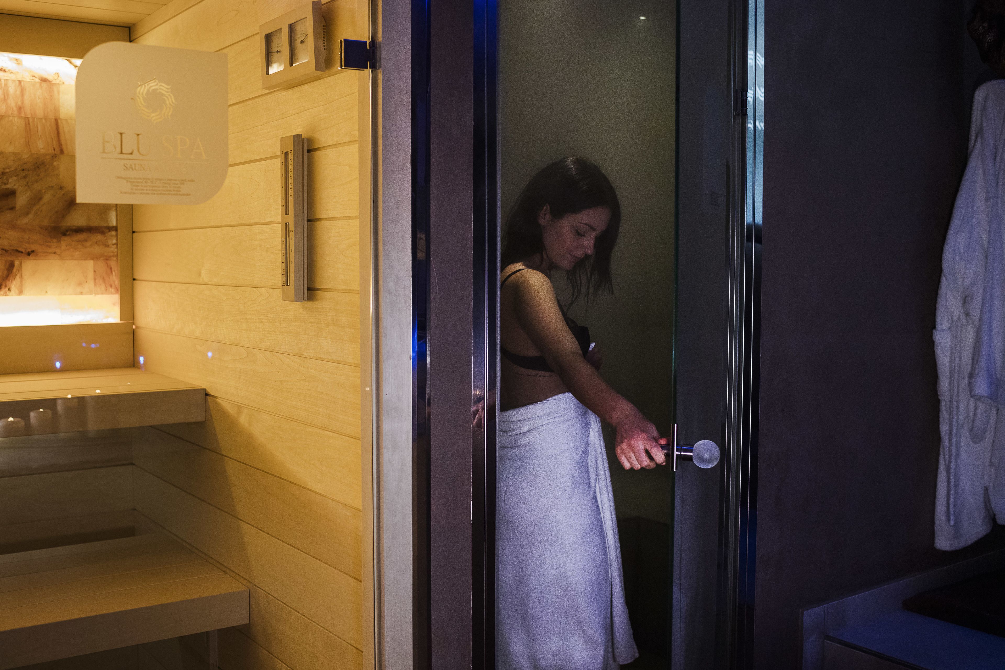 A spa room with a wooden wall, a glass shower enclosure, and a towel hanging on the wall.