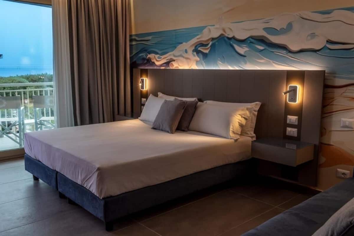 Un dormitorio moderno con una cama grande, una mesita de noche y una lámpara fijada a la pared.