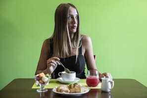 A person sitting at a table with a cup of coffee, a glass of juice, and a plate of food.