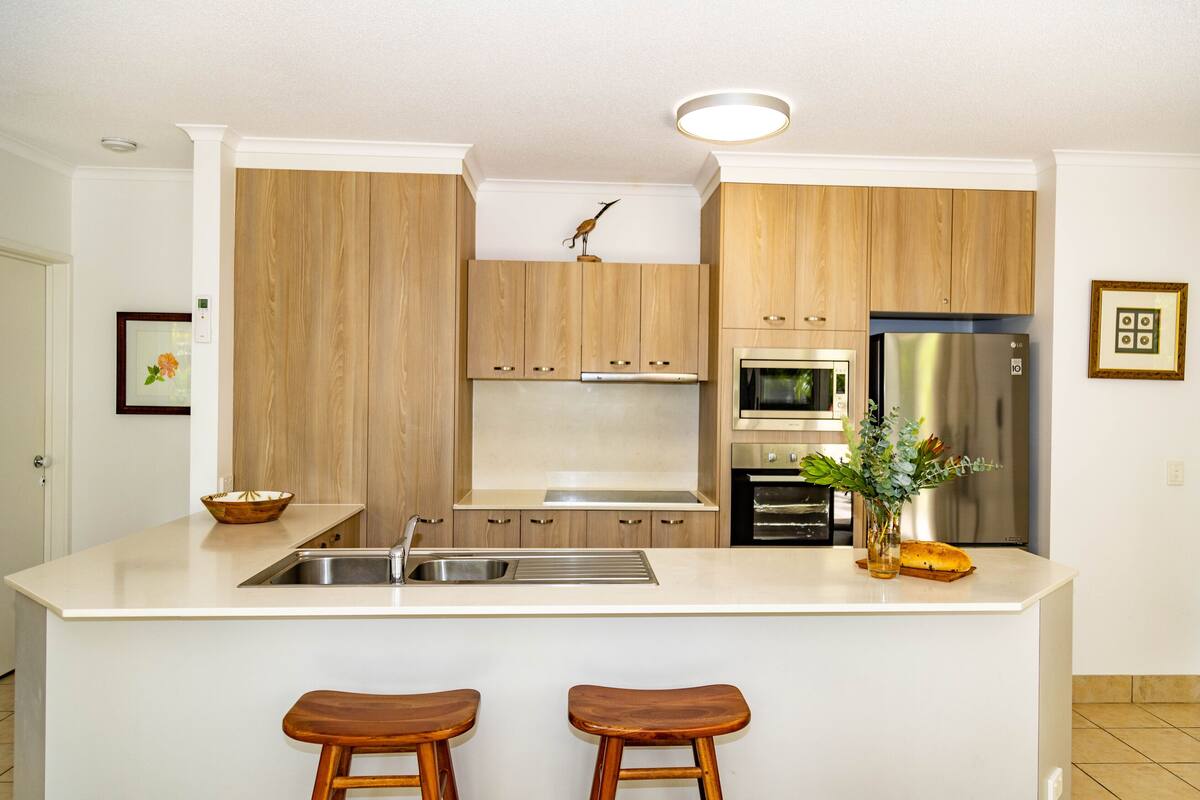 Eine moderne Küche mit Holzausstattung, Edelstahlgeräten und einer zentralen Kochinsel mit Sitzgelegenheiten.
