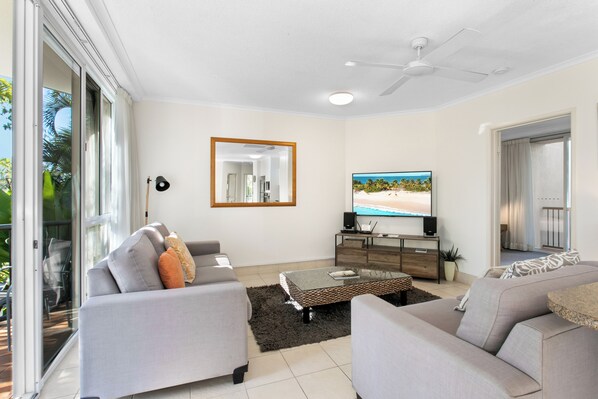 A modern living room with a sofa set, a coffee table, and a flat-screen TV.