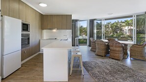 Een moderne keuken met een centraal eiland, houten kasten en een eethoek met rieten meubels.