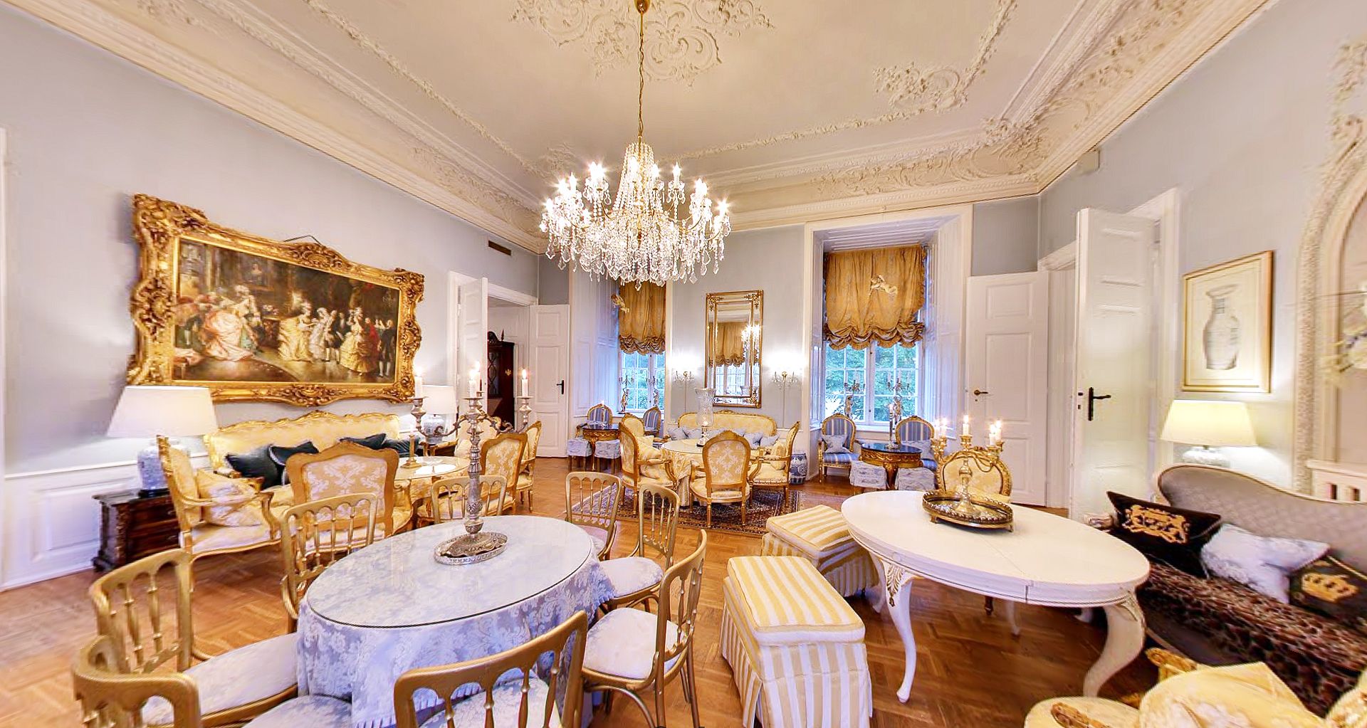 A luxurious room with ornate furniture, a large chandelier, and classical artwork.