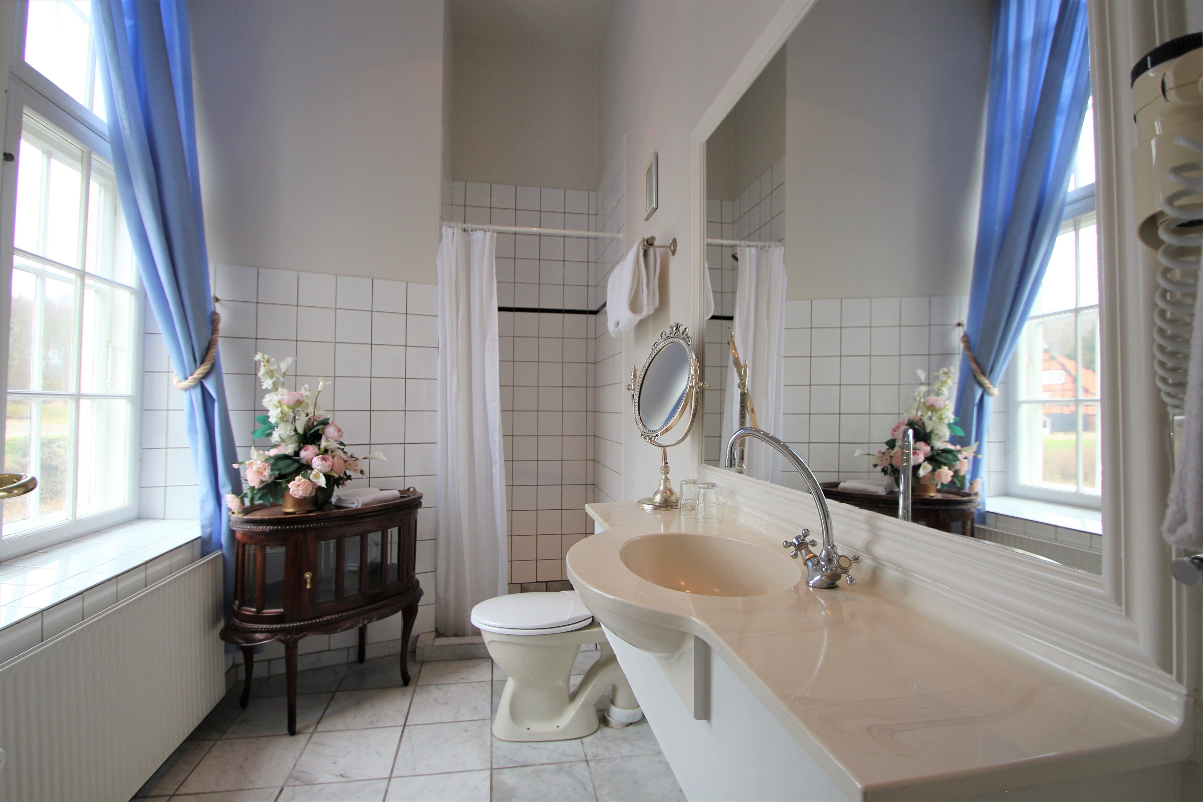 A bathroom with a white sink, a toilet, a vanity with a mirror, and a shower area.