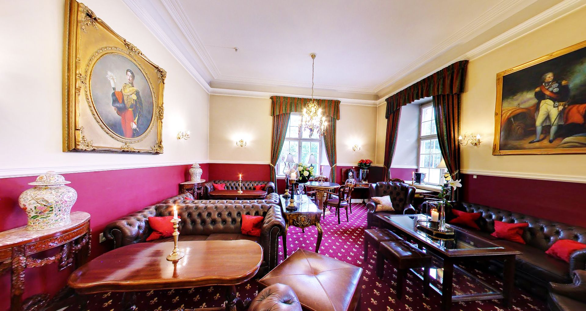 A luxurious room with a red and gold color scheme, featuring a large sofa, a dining table, and a chandelier.