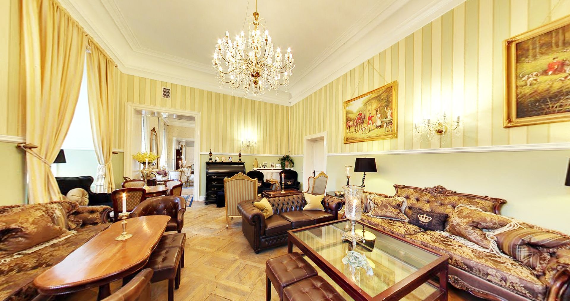 Amplia sala de estar con un gran candelabro, una chimenea y un comedor con muebles de madera.