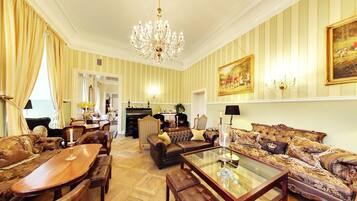 Amplia sala de estar con un gran candelabro, una chimenea y un comedor con muebles de madera.