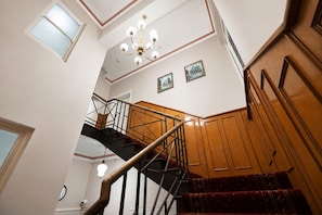 A staircase with wooden railings and a chandelier. - Georgian Court Inn (East Melbourne)