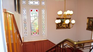 Una escalera con barandilla de madera y una puerta de cristal con un vitral.