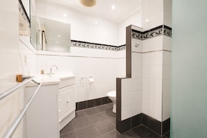 A modern bathroom with a sink, toilet, and shower. - Georgian Court Inn (East Melbourne)