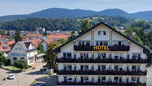 Een hotel met meerdere balkons, uitzicht op de omliggende stad en bergen, en een heldere lucht.