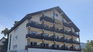 Een meerlaags hotel met balkons, een bord waarop Stadt Gernsbach staat en een heldere lucht.