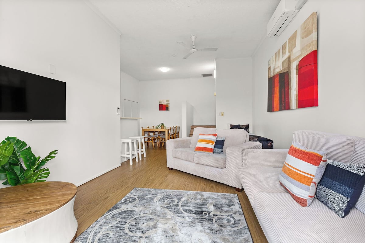 A modern living room with a sofa, a coffee table, and a flat-screen TV.