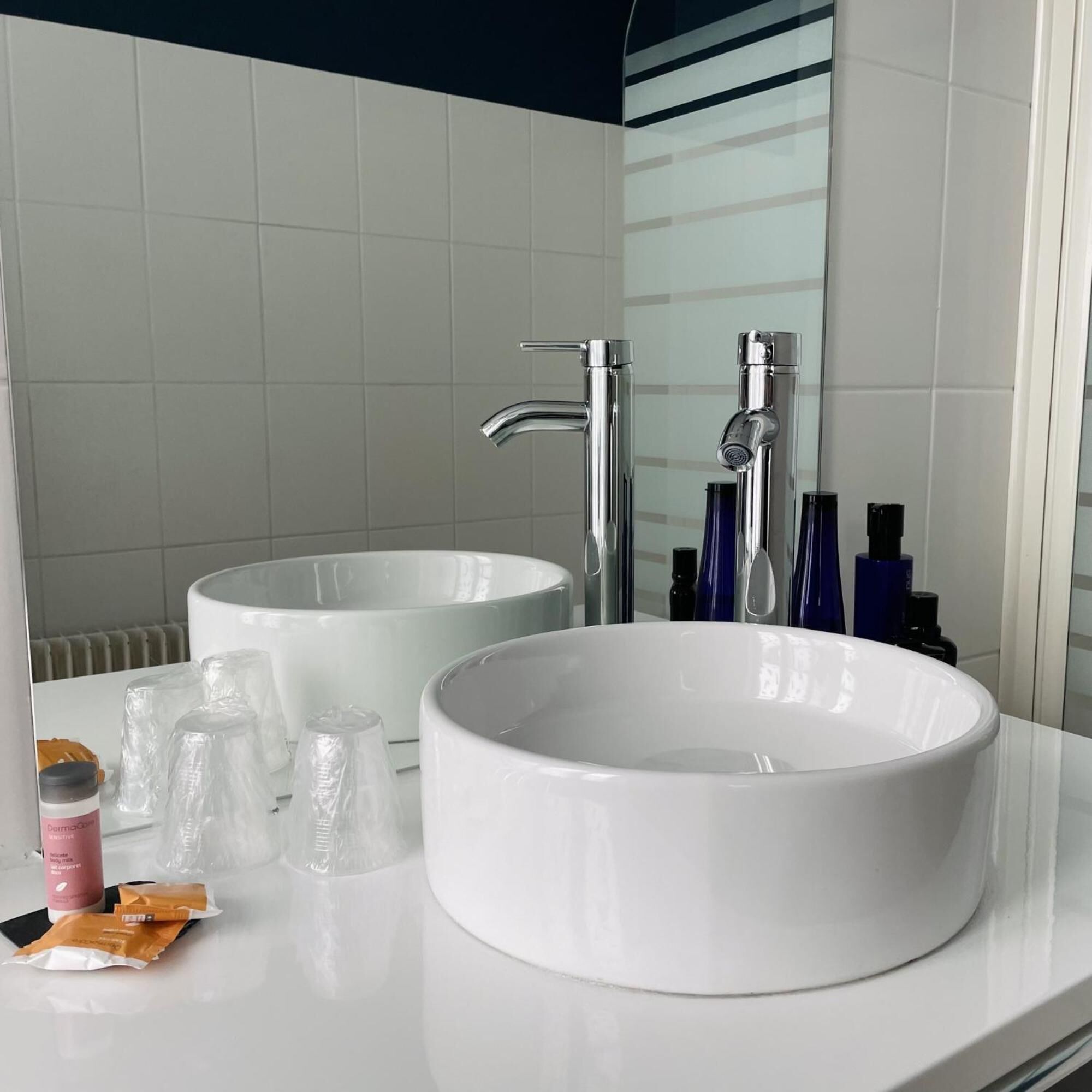 A bathroom with two white sinks, a mirror, and toiletries on the counter.