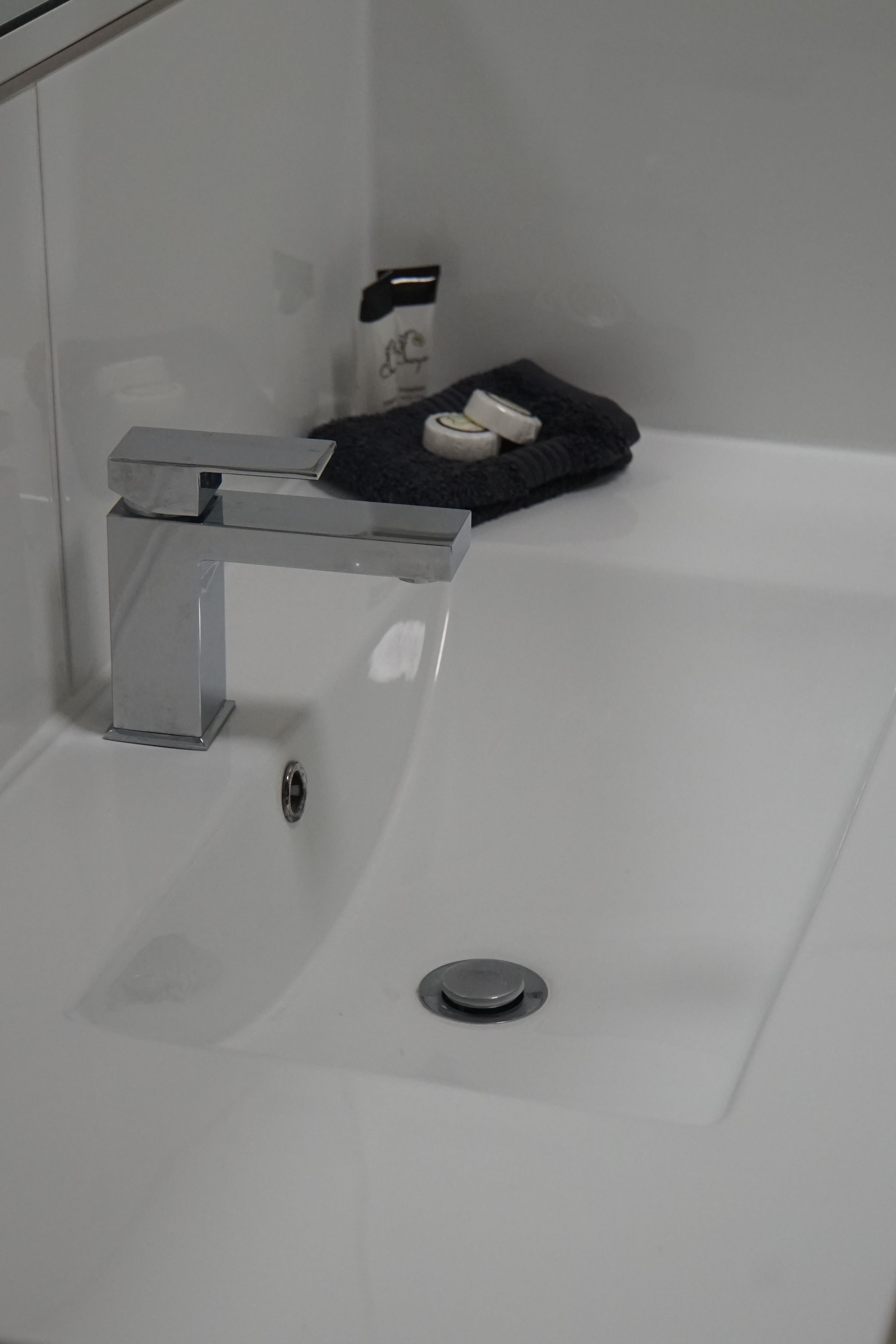 A modern bathroom with a chrome faucet, a white sink, and a black towel on the edge.