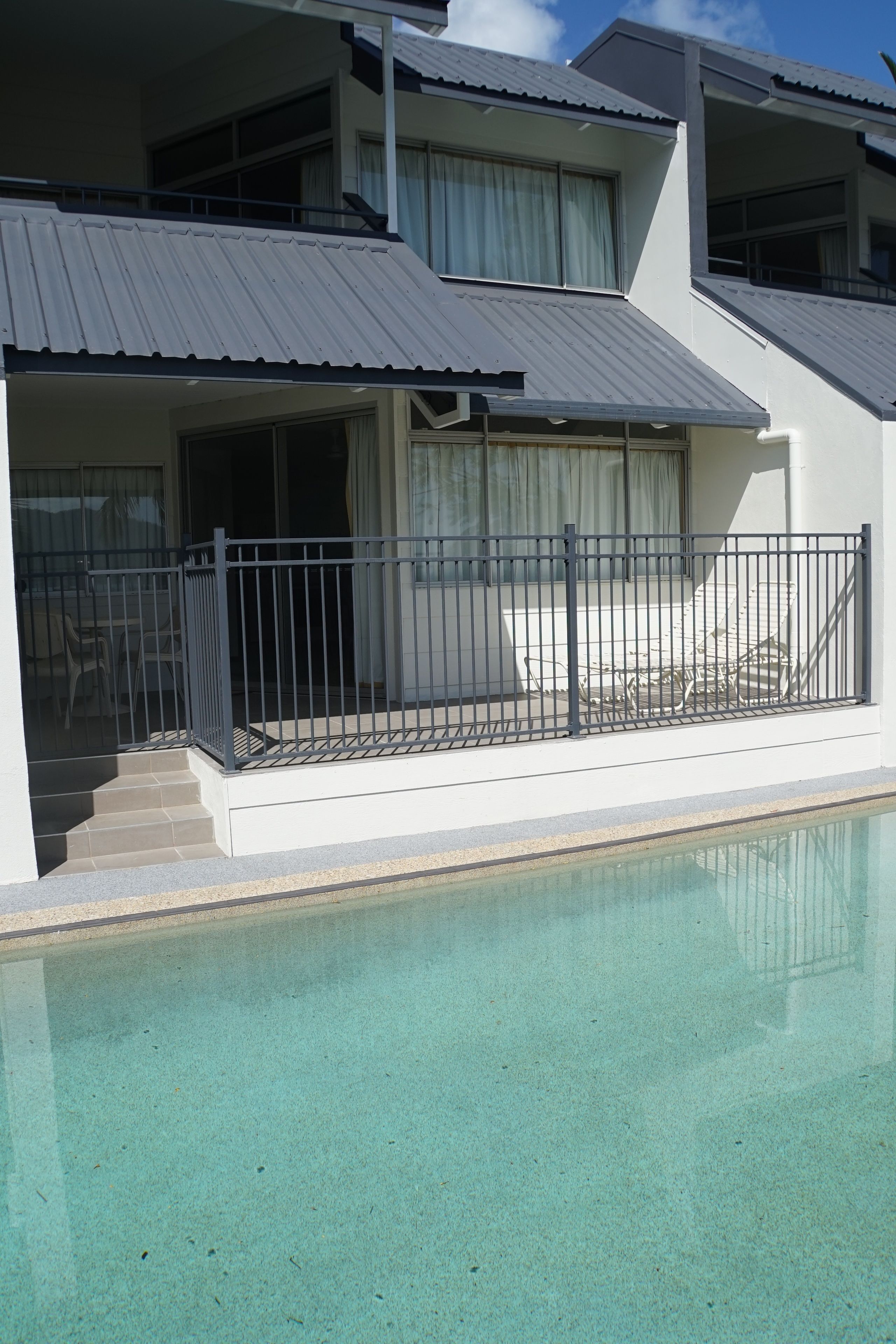 Una piscina al aire libre, sillones reclinables de piscina