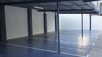Un'area di parcheggio vuota con posti delimitati e una struttura metallica a copertura.