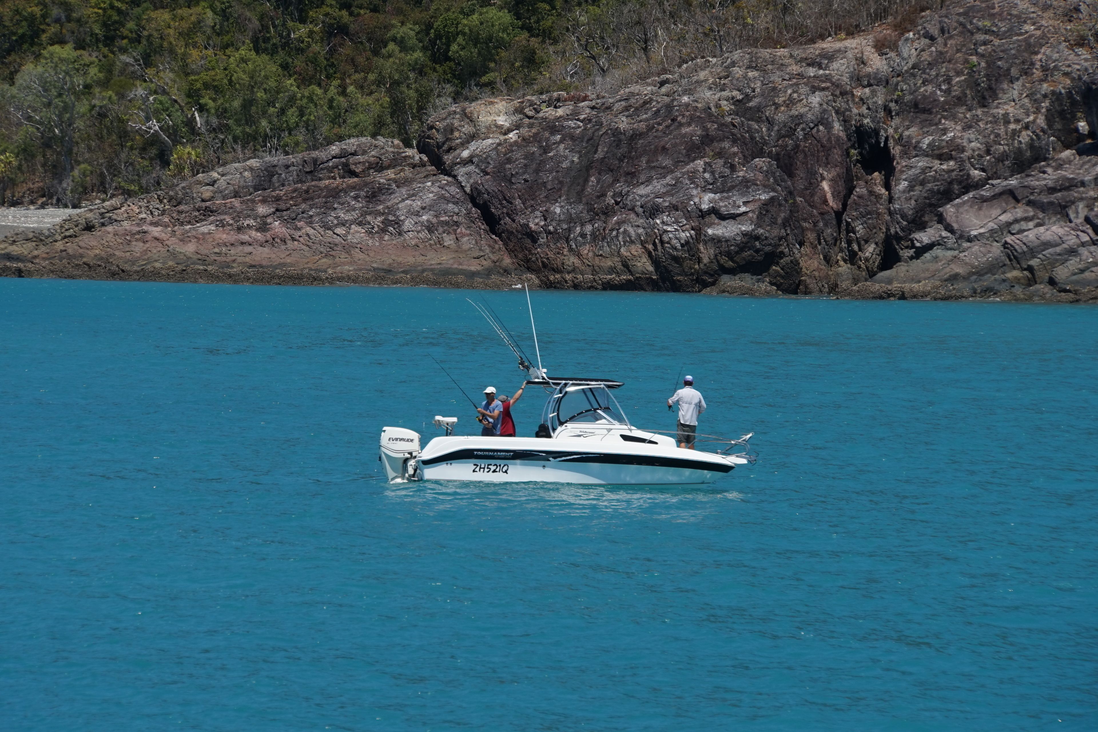 Un bote sobre aguas tranquilas, con terreno rocoso al fondo.